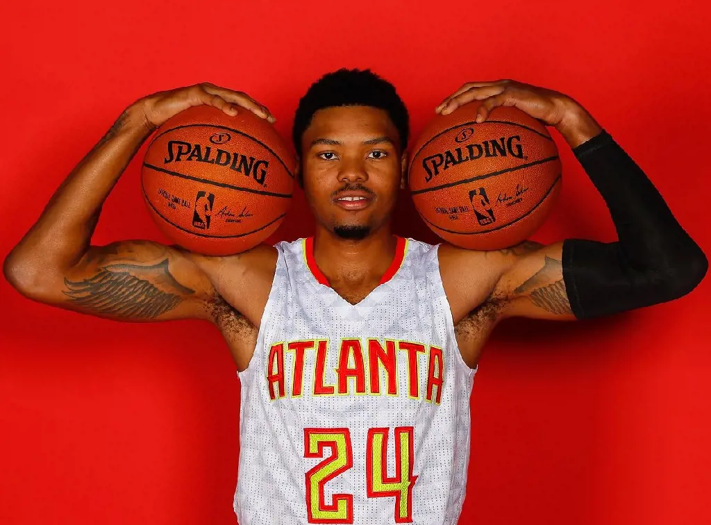 Kent holds two Spalding basketball and shows his wings inked inside his biceps