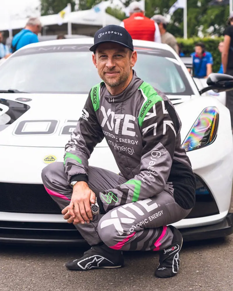 Jenson Button posing in front of a racing car at Lotus Stand s an porting an Xite race suit