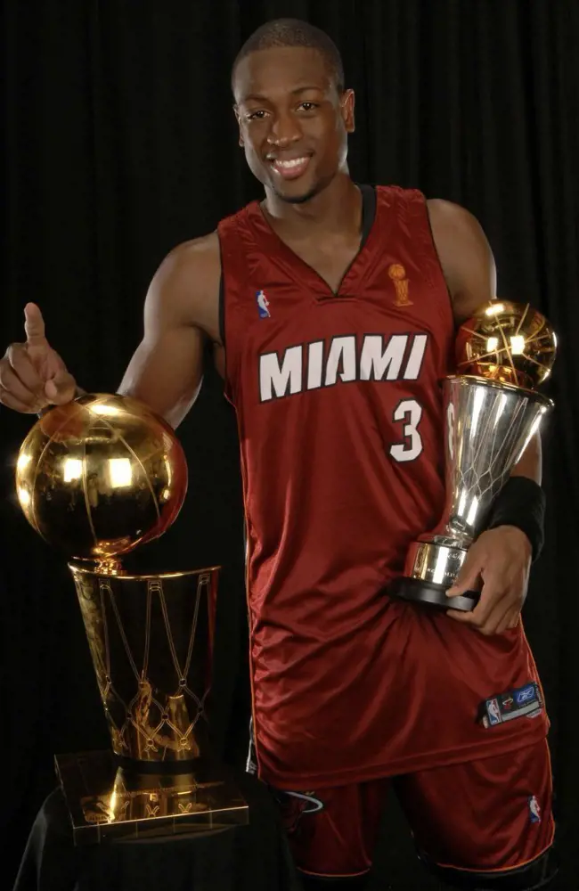 Dwyane holding the basketball chmapionship trophy.