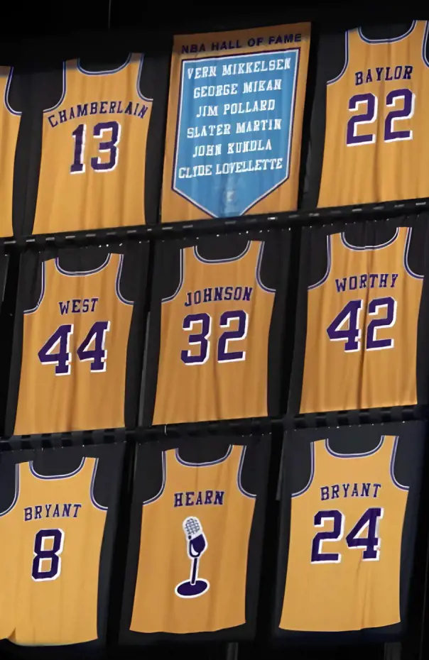 A banner with retired numbers of basketball legends in the rafters of an NBA arena.