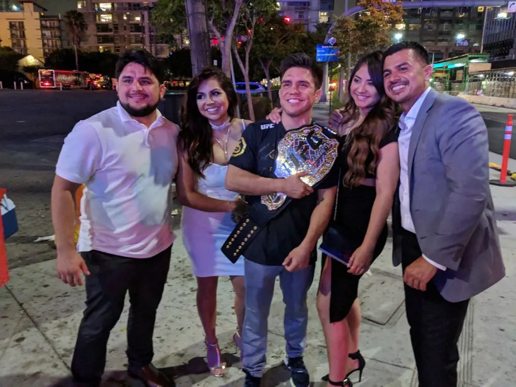 Henry holds his UFC Bantamweight belt as he takes picture with Angel, Gloria and Christy in August 2018