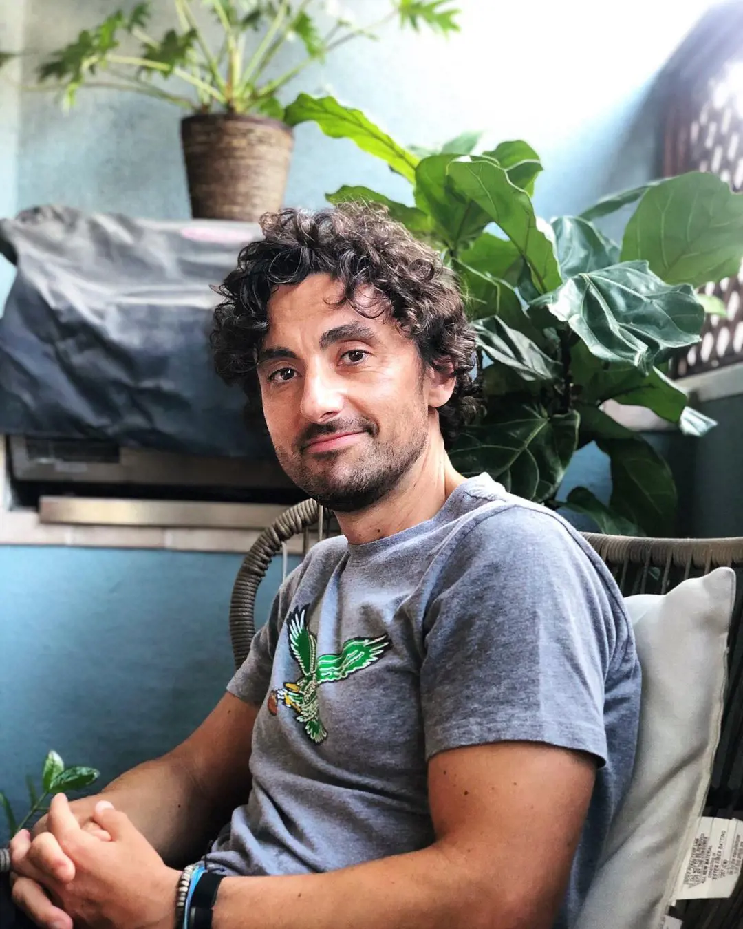 John looking handsome with curly hair and grey tshirt.