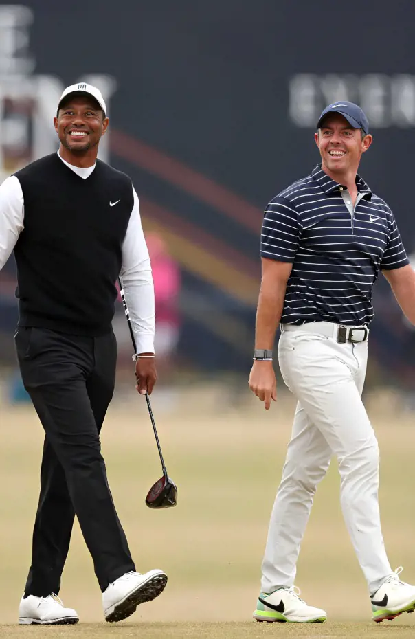 Tiger and Rory sharing a light moment in a golf course.