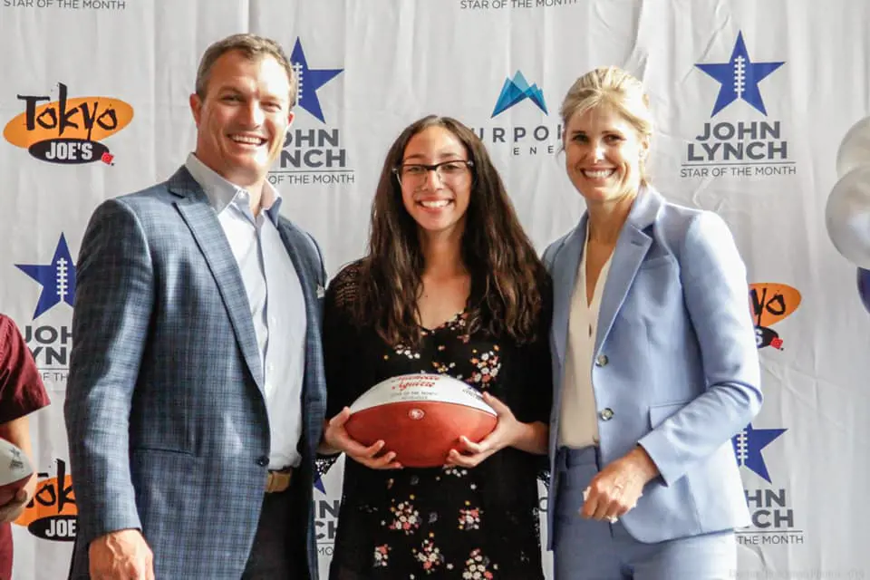 John (left) and Linda (right) providing a rugby ball to a girl through their foundation in May 2019