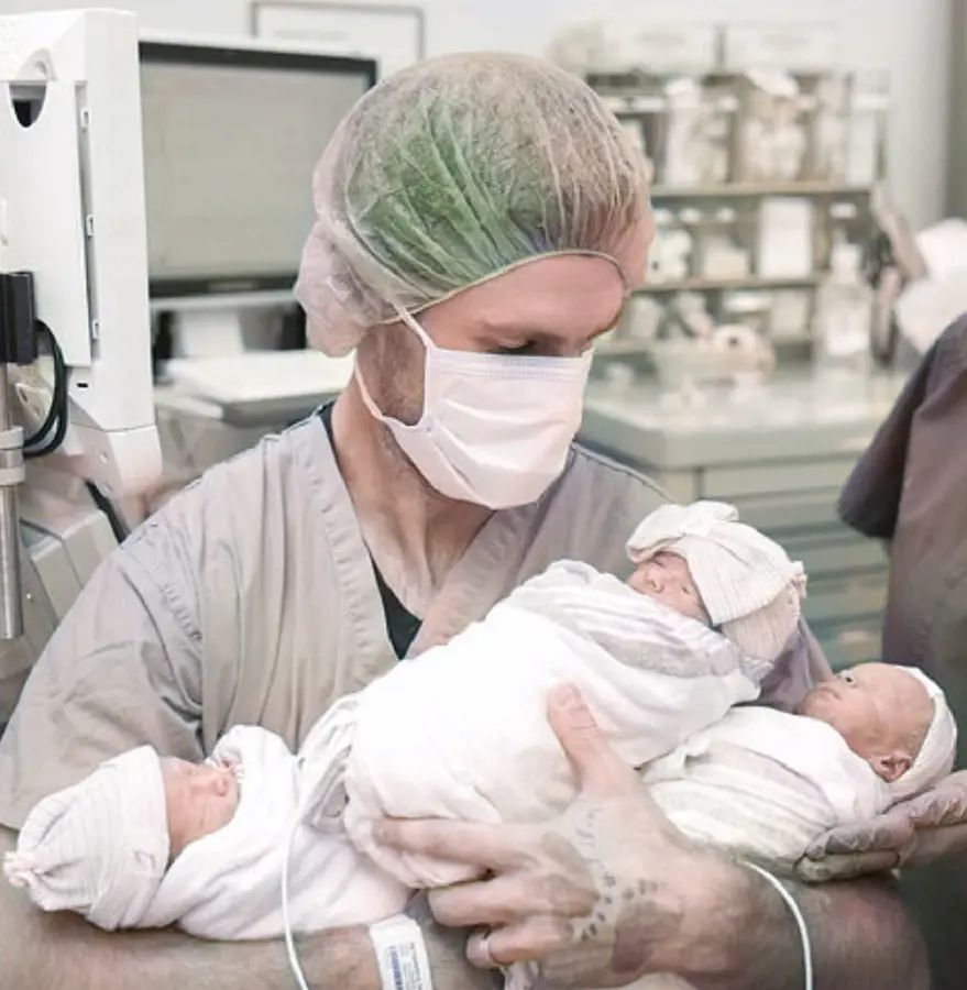 Alex holds the triplets Evelyn, Oliver, and Theodore in 2017