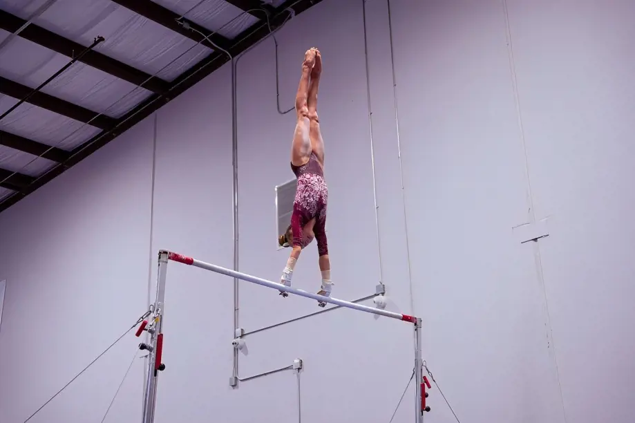 A gymnast performing an acrobatic maneuver on the bar